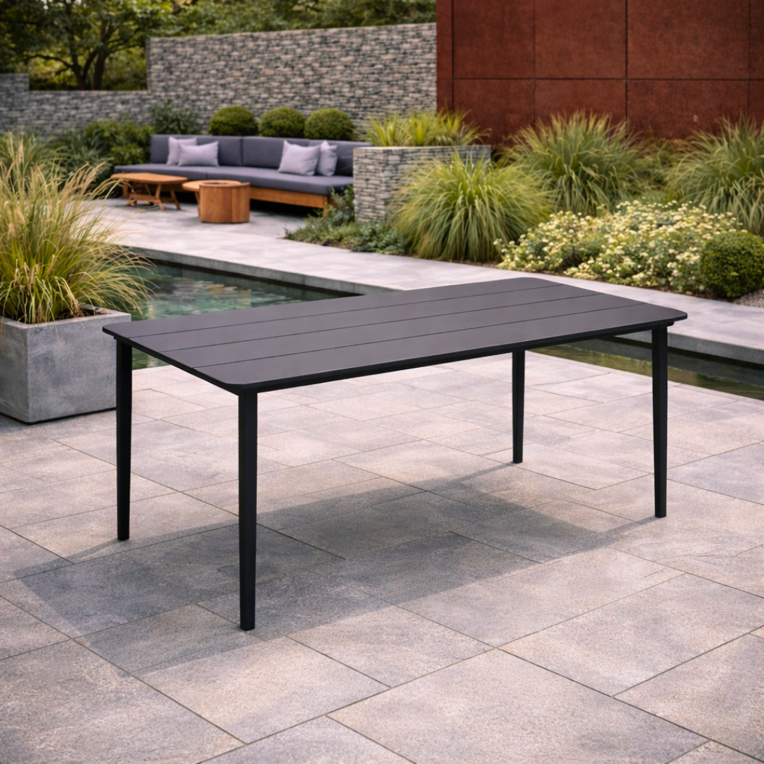 Black outdoor dining table on a patio with garden and pool in the background