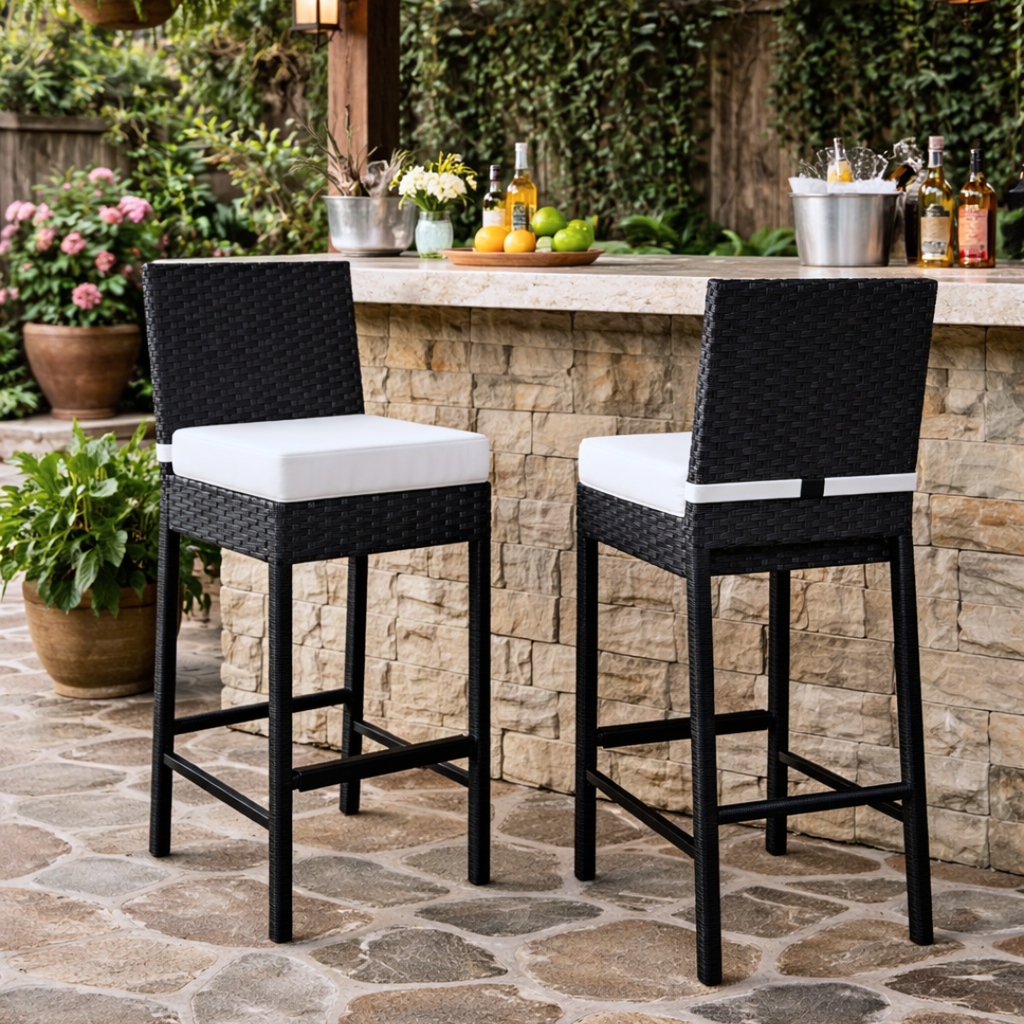 Two black outdoor bar stools with white cushions in front of a stone outdoor bar.