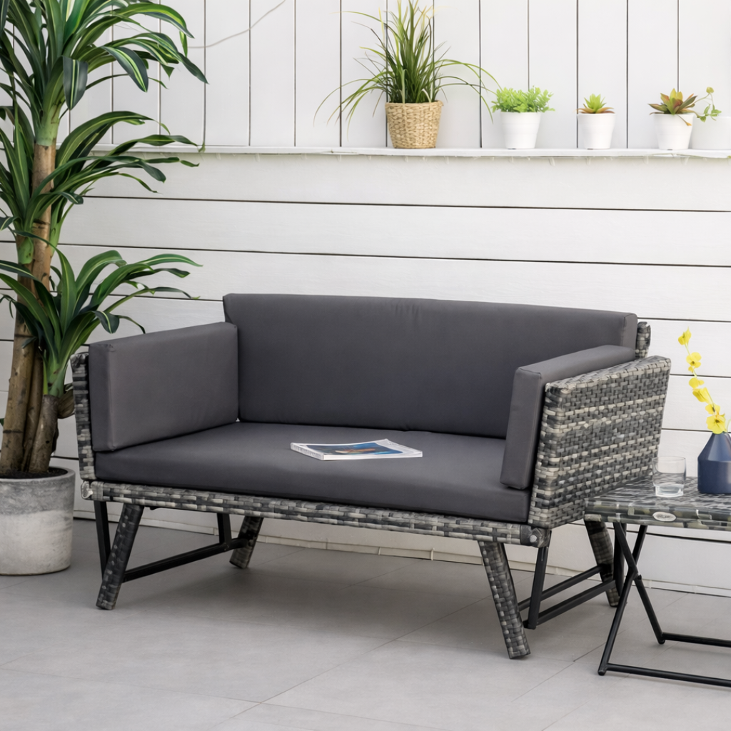 Gray outdoor sofa with cushions on a patio with plants and a small table.