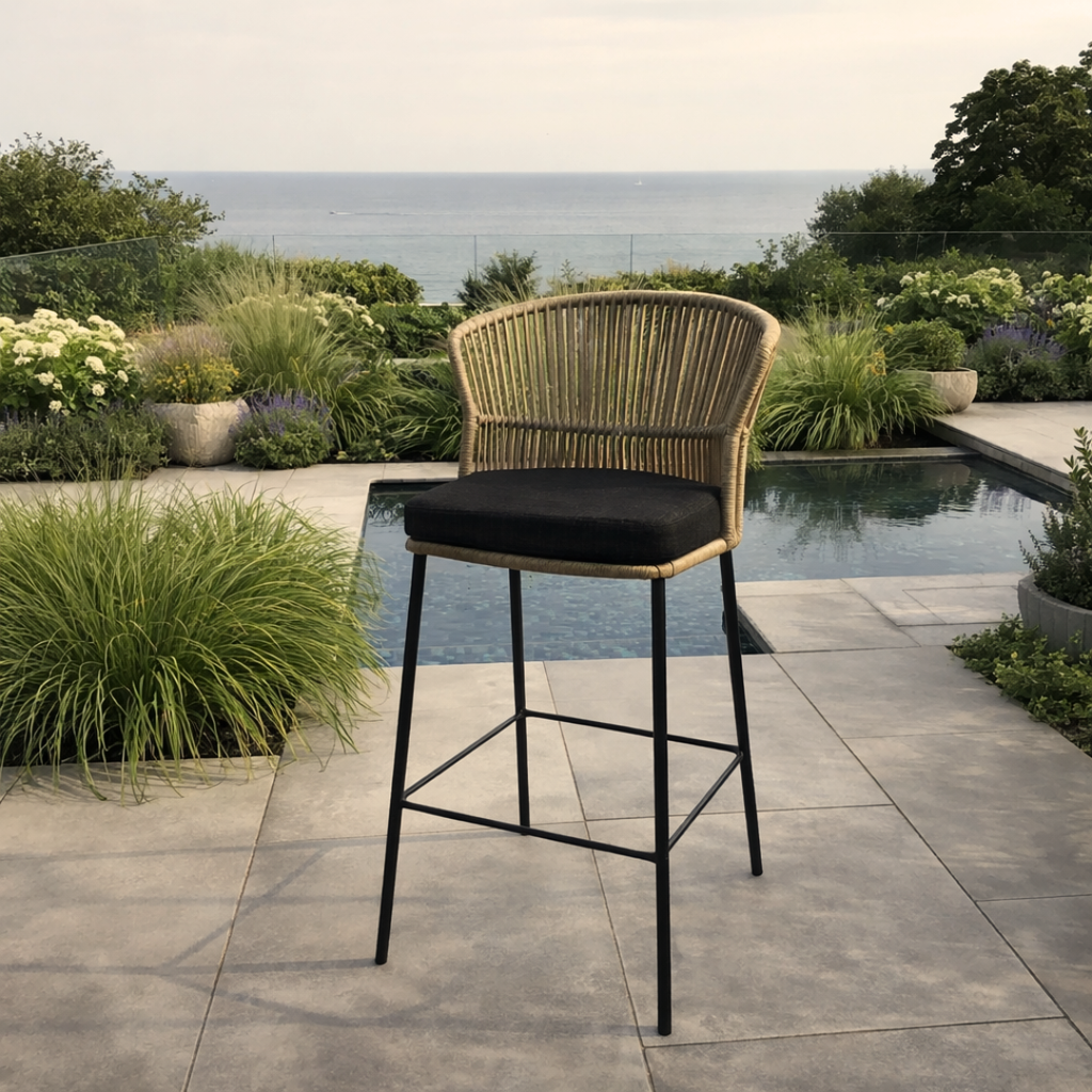 Wicker bar stool with black cushion on a patio with pool and garden view