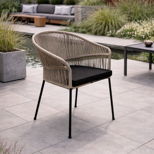 Wicker chair with black cushion on a patio area with plants and furniture in the background