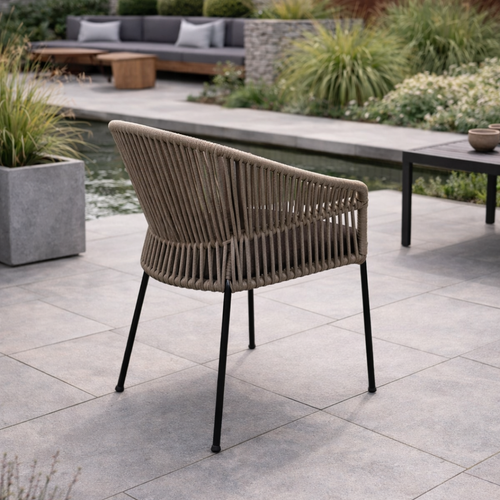 Woven outdoor chair on a patio with garden and seating area in the background