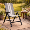 Black and white patterned chair in a garden setting with a small table and plants.