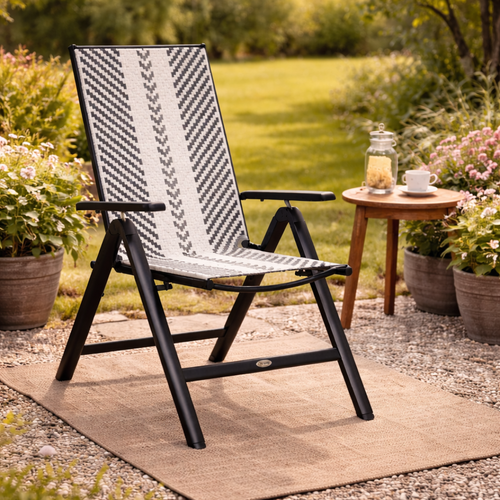 Black and white patterned chair in a garden setting with a small table and plants.