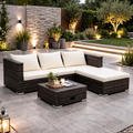 Outdoor patio with wicker sectional sofa, coffee table, and decorative elements in a garden setting.