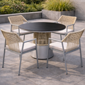 Outdoor patio set with round table and four chairs on a stone patio.