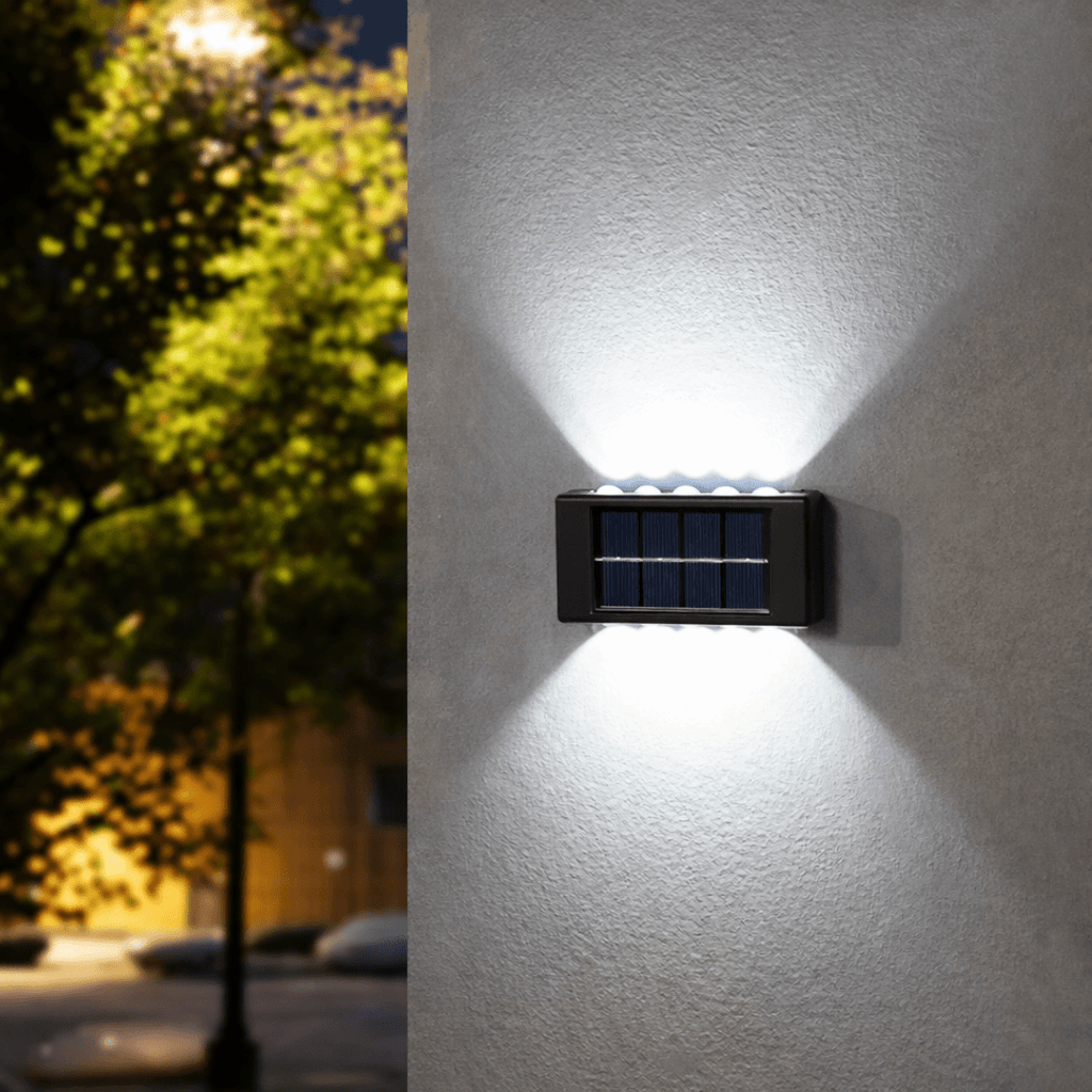 Solar-powered outdoor wall light fixture on a building exterior at night.