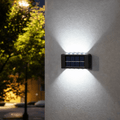 Solar-powered outdoor wall light fixture on a building exterior at night.