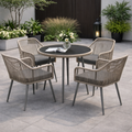Outdoor patio set with round table and four chairs on a stone patio.
