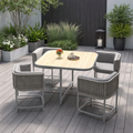 Outdoor patio set with table and chairs on a wooden deck, surrounded by plants.