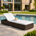 White cushioned lounge chair with a straw hat and towel by a poolside.