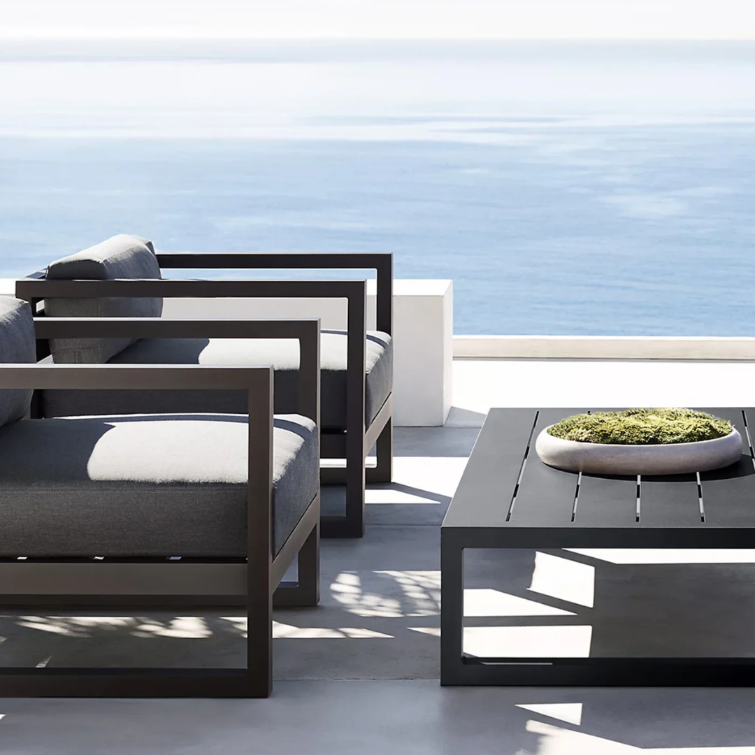 Modern aluminum garden coffee table for stylish seating areas in a coastal garden background. 