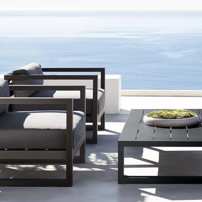 Modern aluminum garden coffee table for stylish seating areas in a coastal garden background. 