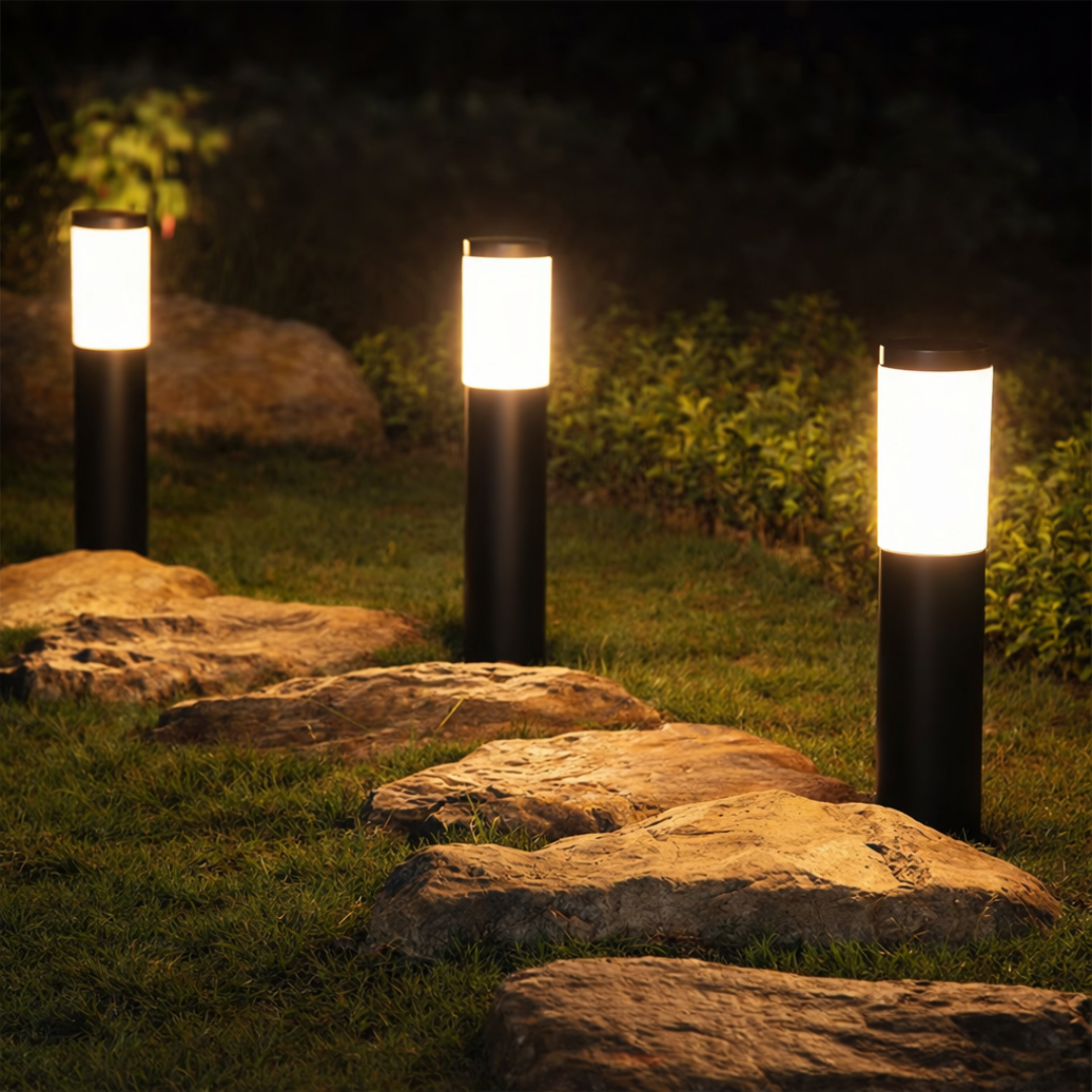 Three garden lights illuminating a pathway made of stones at night.
