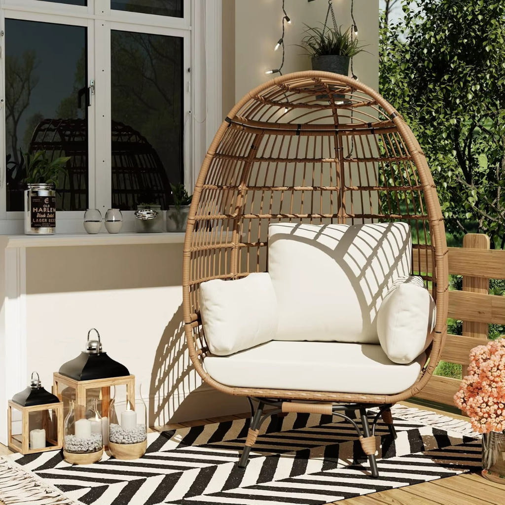 A modern wicker garden egg chair with beige cushions, set in a modern garden with decking.