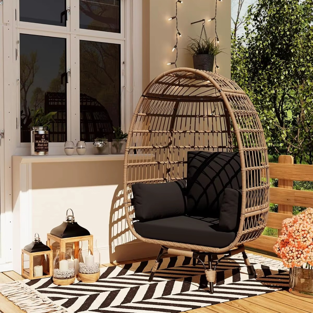 A modern wicker garden egg chair with black cushions is set in a garden with ornaments and decking.