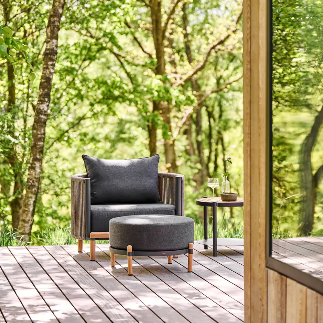 Outdoor rope furniture set with cushioned seating, photo shows the armchair, foot pedal and side table together, in a luxury outdoors background