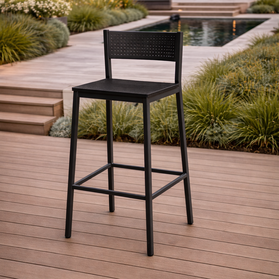 Black bar stool on a wooden deck with a garden and pool in the background