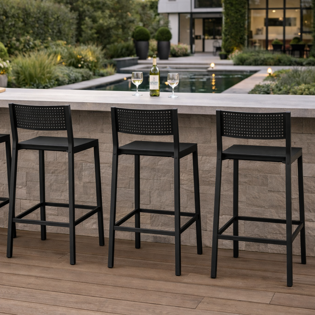 Black outdoor bar stools in front of a modern patio with a pool and garden.