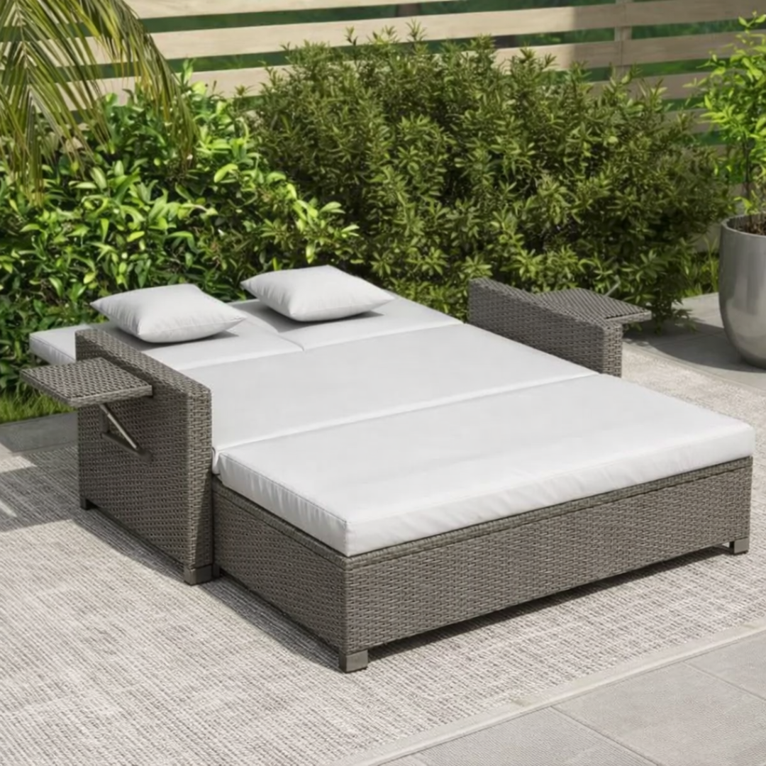Outdoor lounge bed with white cushions on a patio area with greenery in the background